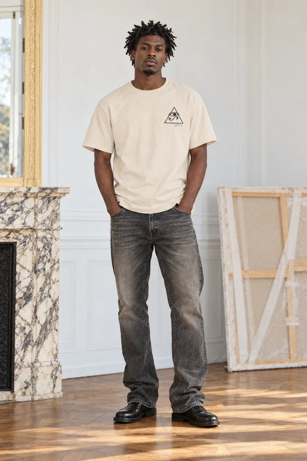 Fictional model wearing the soft cream Eye of Horus tee in an artist studio